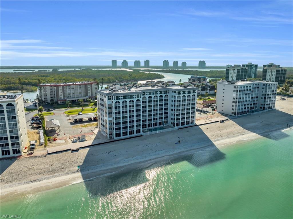 Beachfront multi-story building featuring arched window details, a flat roofline, and direct beach access