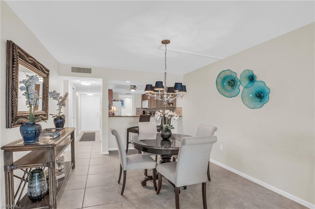 Dining area featuring tiled flooring, a decorative ceiling fixture, and a pass-through opening to an additional space
