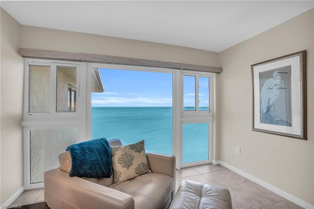 Floor-to-ceiling windows offering expansive water views, complemented by light-toned wall paint and tile flooring