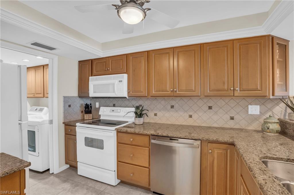 Kitchen featuring wood cabinetry, stone countertops, stainless steel dishwasher, white electric range, and a patterned tile backsplash