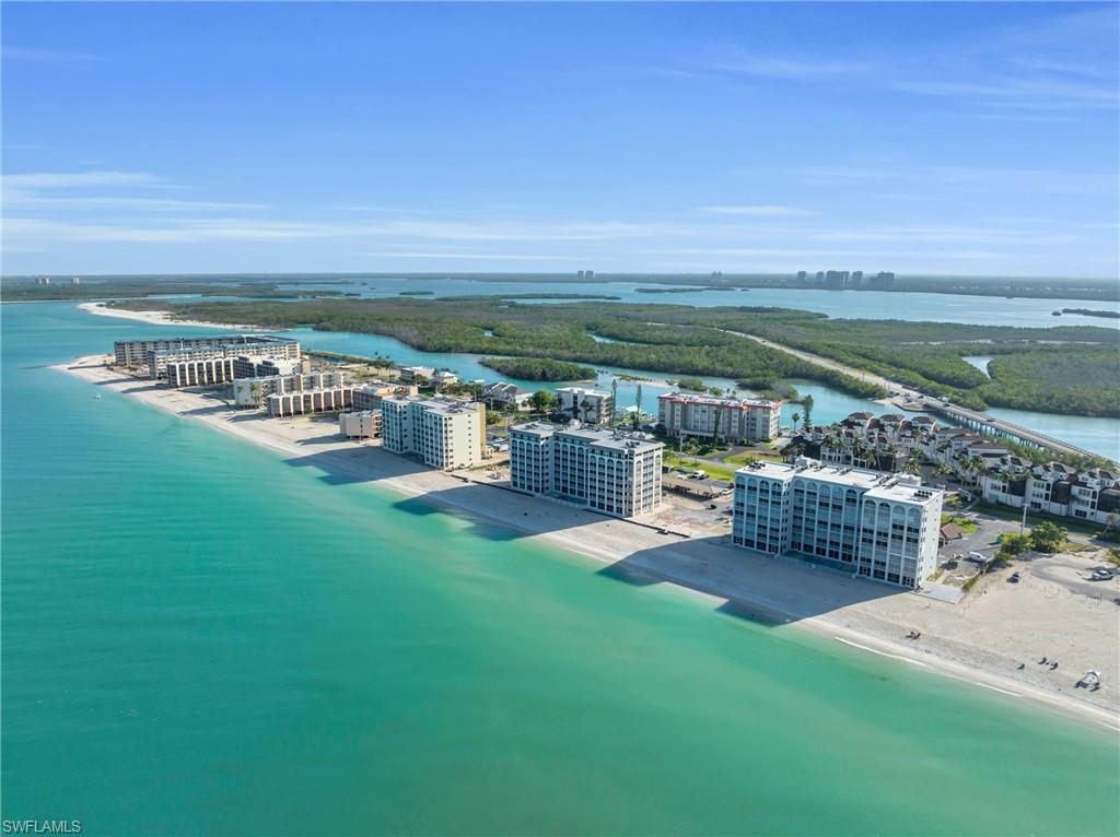 Coastal condominium buildings positioned directly on a sandy beach, with expansive turquoise waters