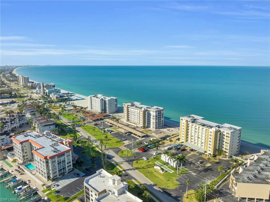 Coastal community featuring multiple multi-story residential buildings, ample surface parking, and manicured green spaces