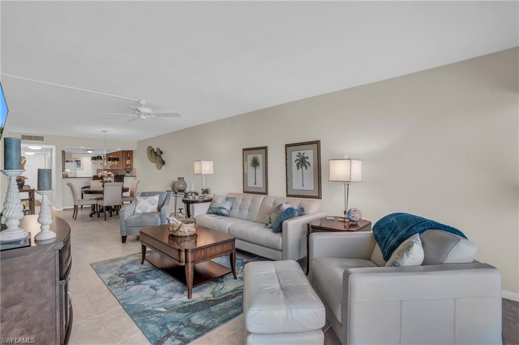 Open-concept living space featuring neutral wall tones, tile flooring, a dining area with a chandelier, and a ceiling fan