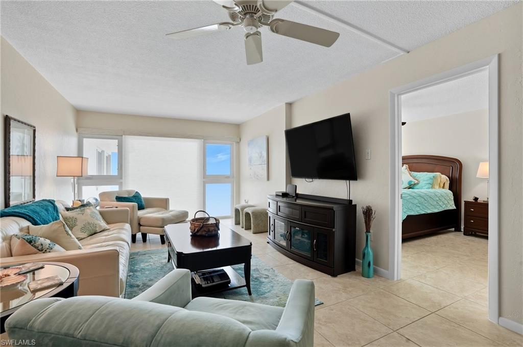 Living area featuring light-toned walls, tile flooring, and a ceiling fan