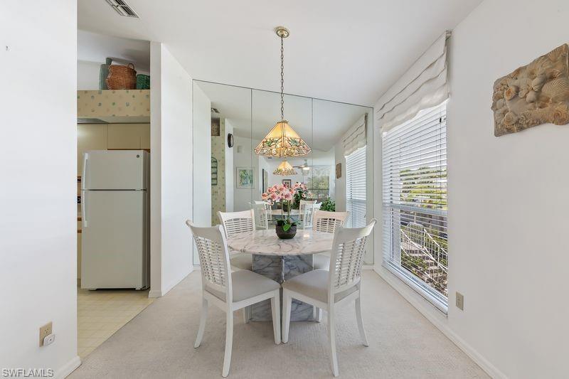 Dining area featuring a full-height mirrored wall, a window with horizontal blinds, and carpet flooring.