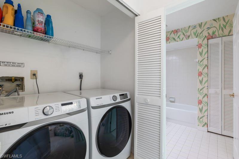 Dedicated laundry area featuring washer and dryer, storage area, white walls, and a louvered bi-fold door.