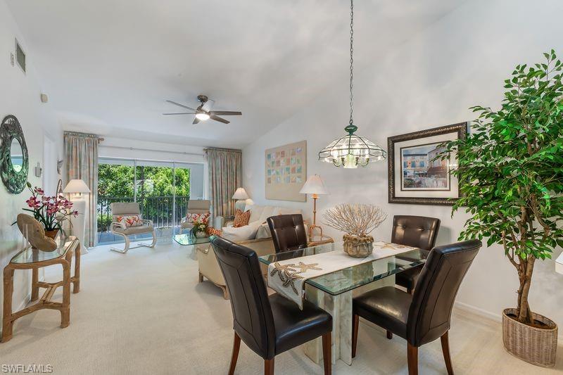Open-concept living and dining area featuring vaulted ceilings, a ceiling fan, with view to screened lanai.