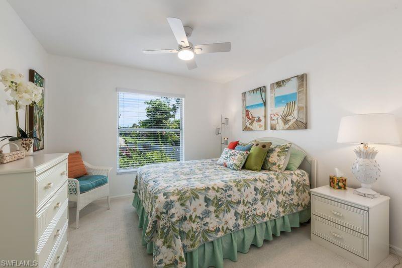 Bright bedroom featuring a new ceiling fan, large window with blinds, and light-toned carpet flooring.