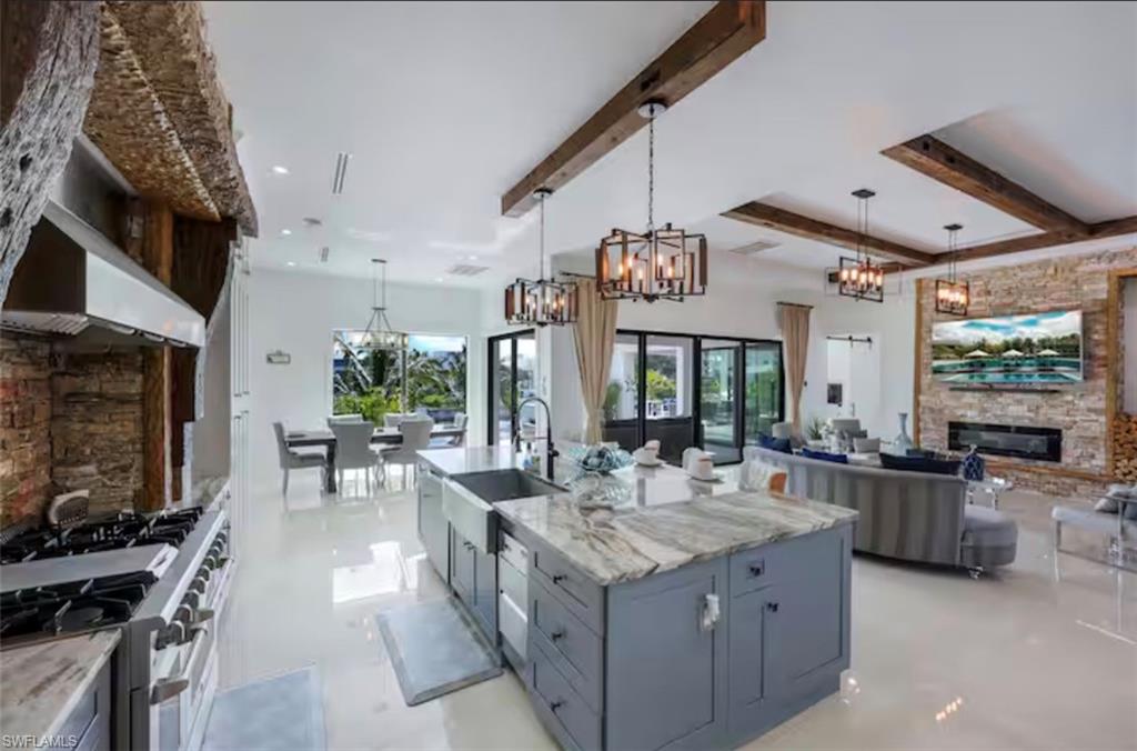 Kitchen with a fireplace, double oven range, light stone counters, open floor plan, and hanging lights