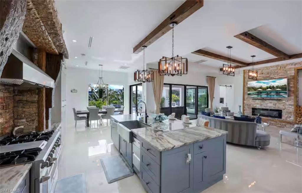 Kitchen featuring a fireplace, double oven range, open floor plan, light stone countertops, and a large island