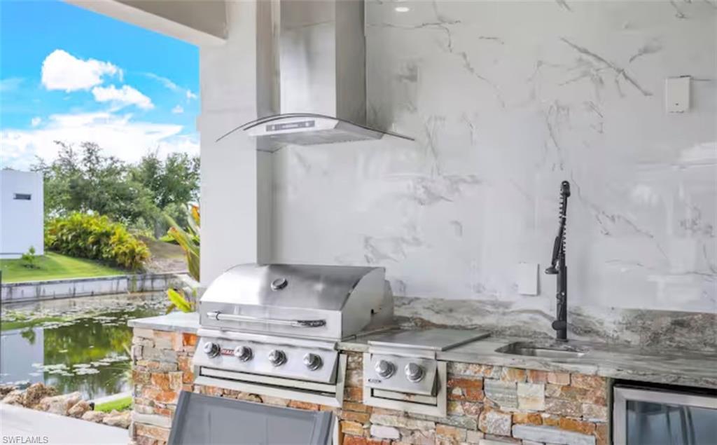 View of patio with an outdoor kitchen and a water view