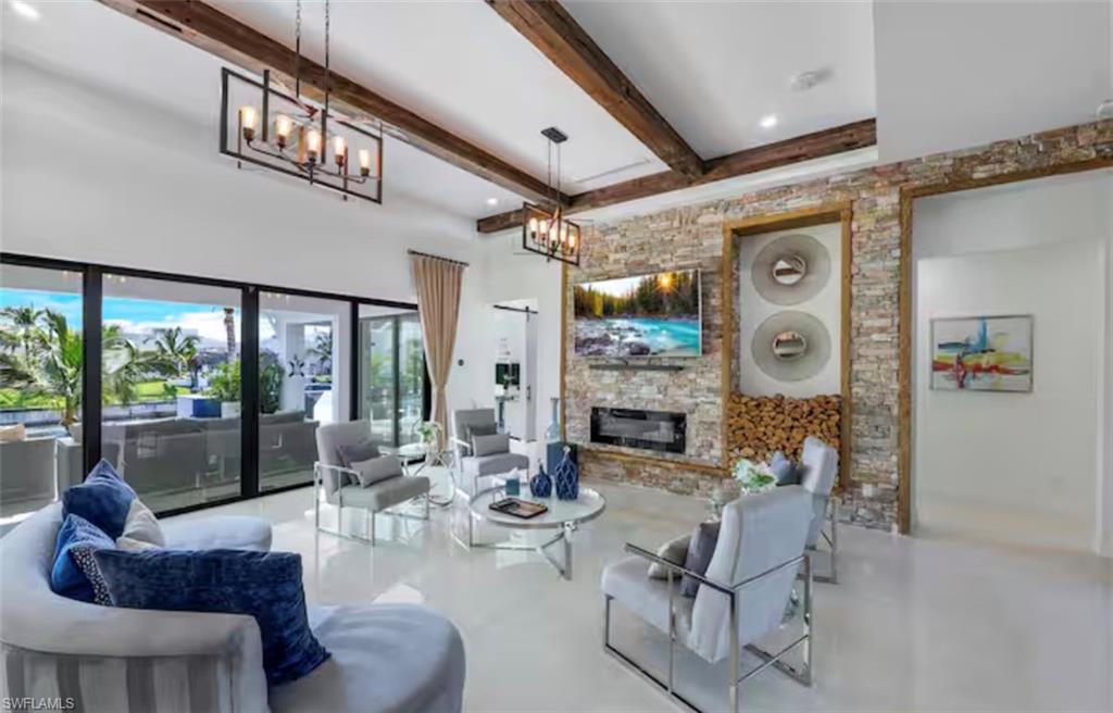 Living area with a stone fireplace, a chandelier, and concrete flooring