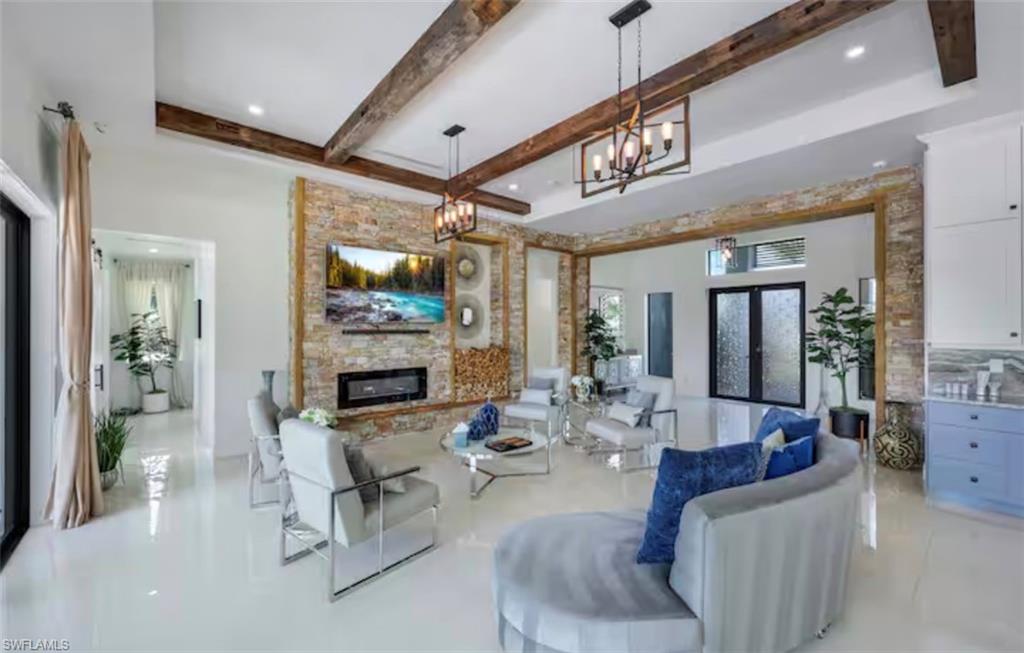 Living room featuring french doors, a fireplace, beamed ceiling, and a chandelier
