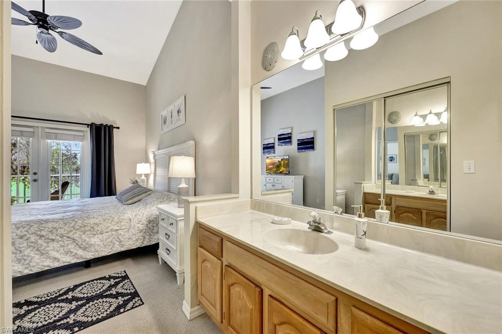 Bathroom vanity featuring a light-toned countertop, wood-finish cabinetry, and a large wall-mounted mirror