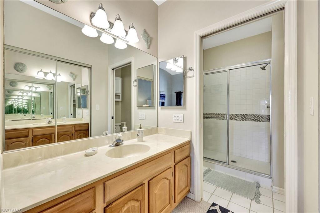Bathroom featuring a double vanity with light wood cabinetry, a light-toned countertop, and a large wall-mounted mirror