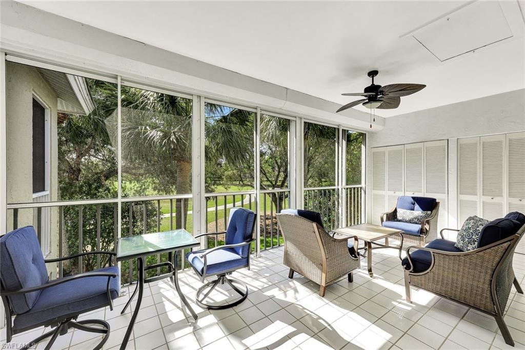 Screened-in outdoor living space featuring a ceiling fan, white tile flooring, and accordion-style louvered doors