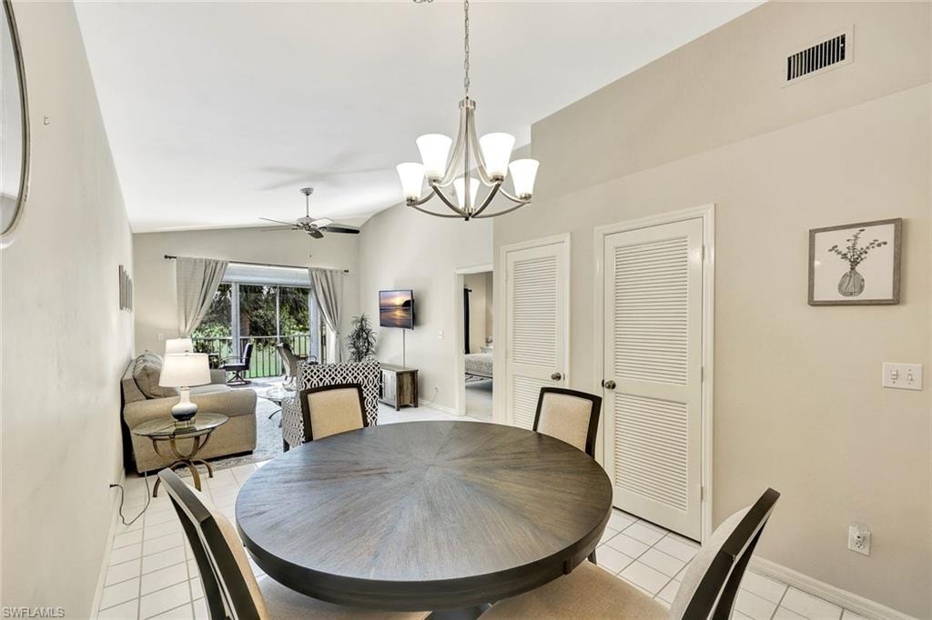 Dining area featuring a contemporary five-light chandelier, a round wood-finish table, and tile flooring