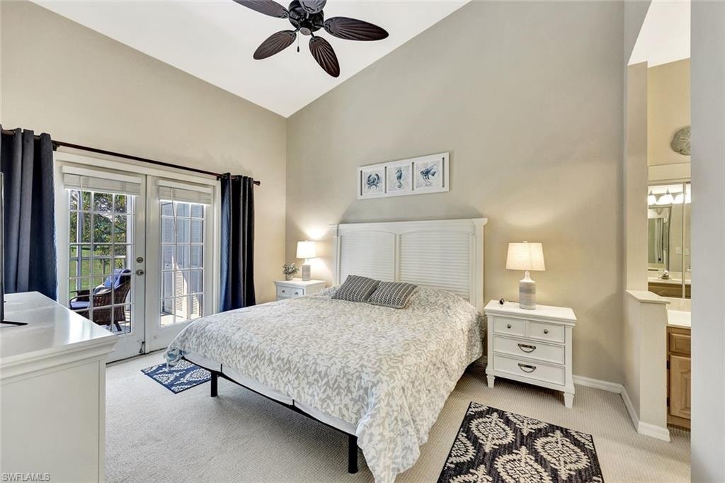 Vaulted ceiling bedroom with light beige carpet and a dark-bladed ceiling fan