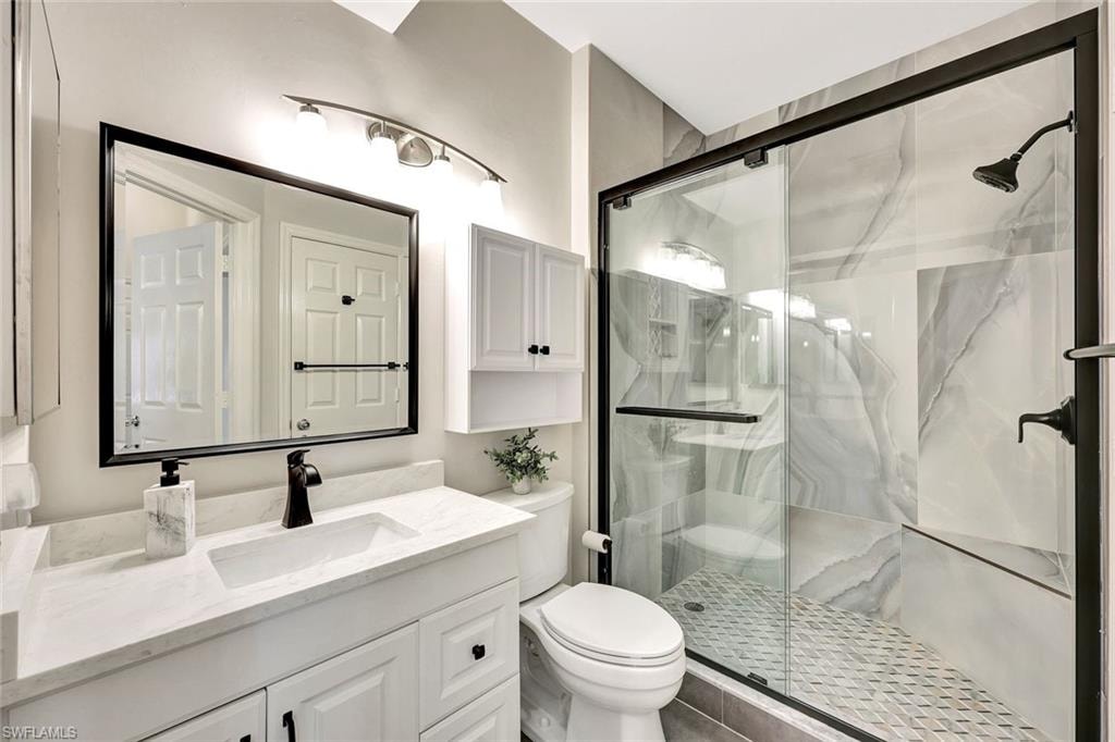 Modern bathroom featuring a glass-enclosed shower with large format wall tiles, a built-in shower bench, and a geometric floor tile pattern