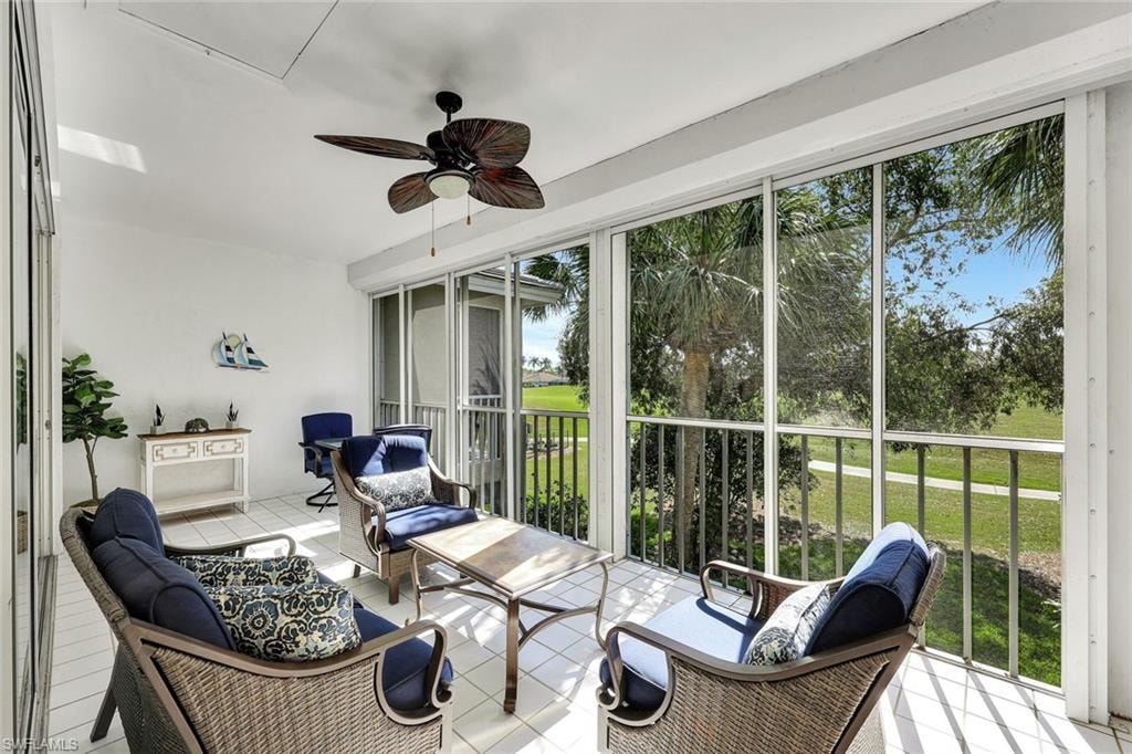 Enclosed lanai featuring a ceiling fan, tiled flooring, and screened panels offering outdoor scenery