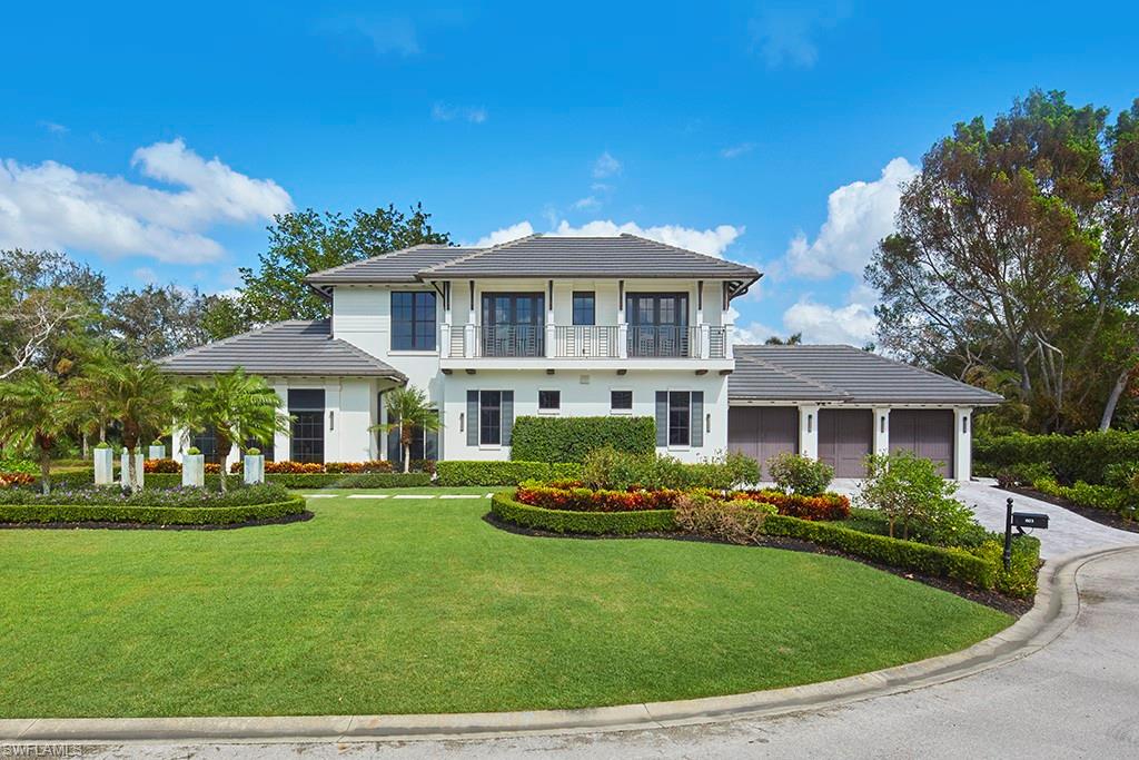 Elegant two-story Colonial residence featuring a crisp white exterior with dark shutters and a covered front portico