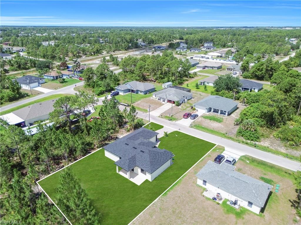 Aerial view showcasing a newly constructed single-story residence with a dark shingle roof and a vibrant green lawn