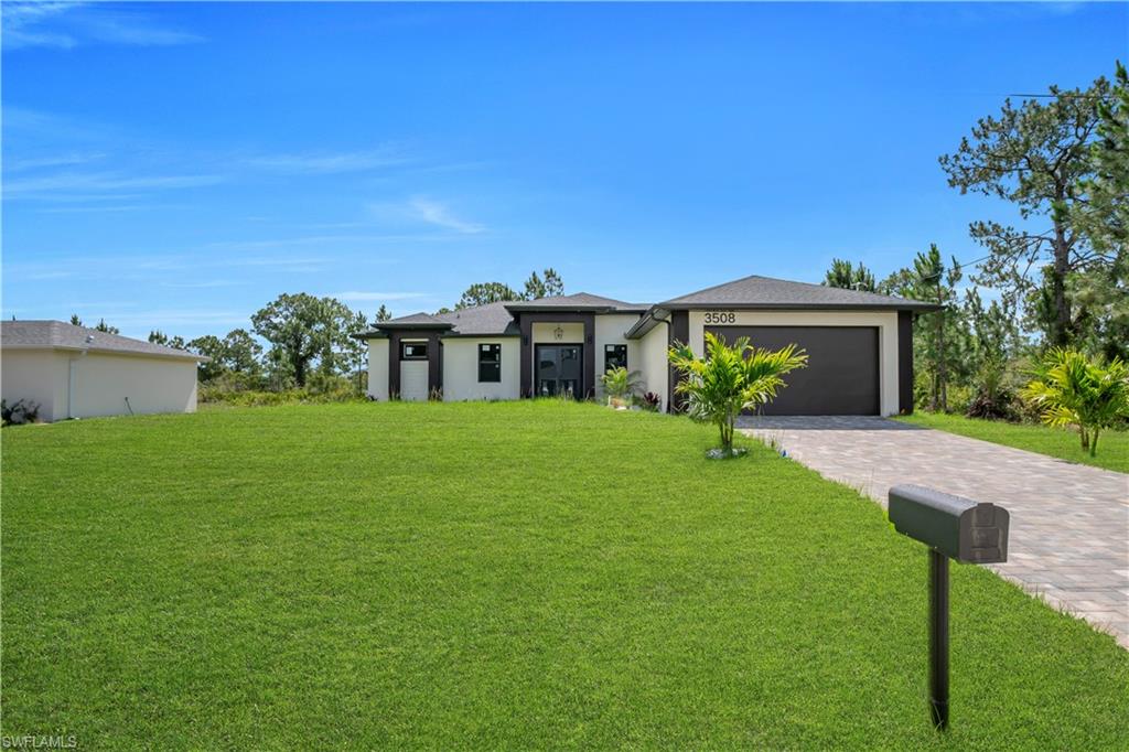 Modern ranch-style exterior with a dark-pitched roof, attached two-car garage, and a paver driveway