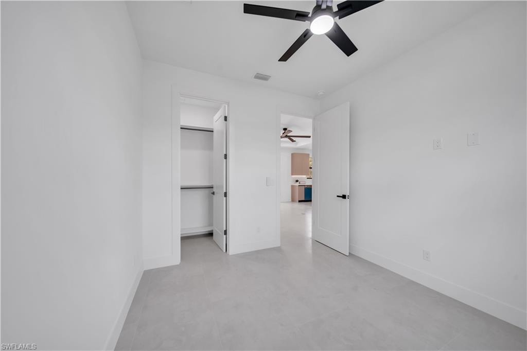 Room featuring light-toned flooring, white walls, and a modern ceiling fan with integrated lighting