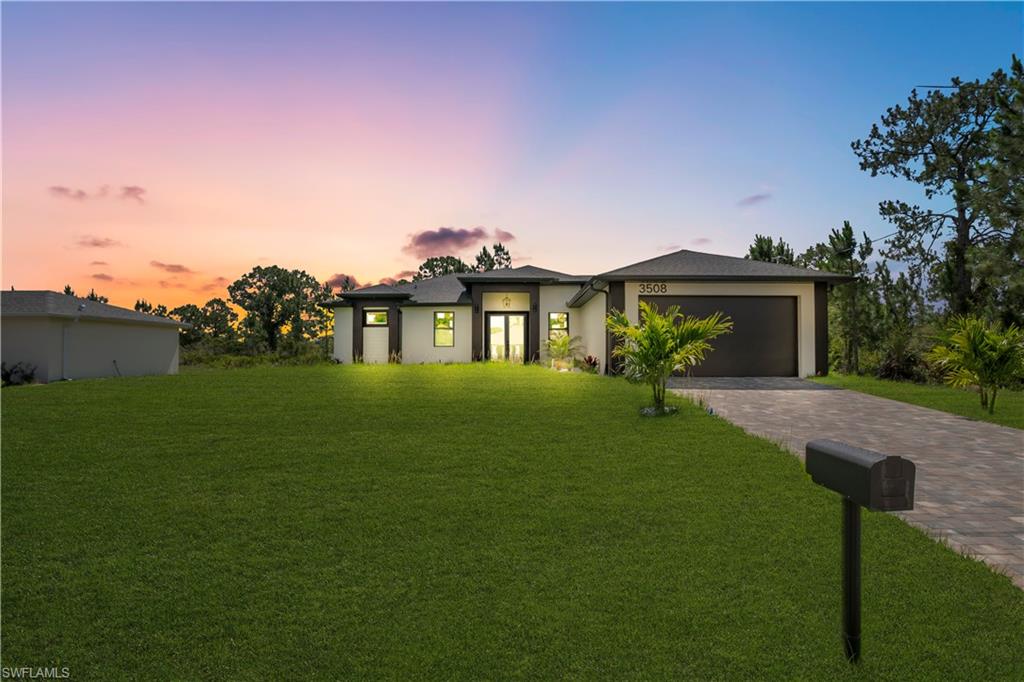 Modern exterior featuring a dark gray garage door, a paved driveway, a manicured lawn, and low-maintenance landscaping