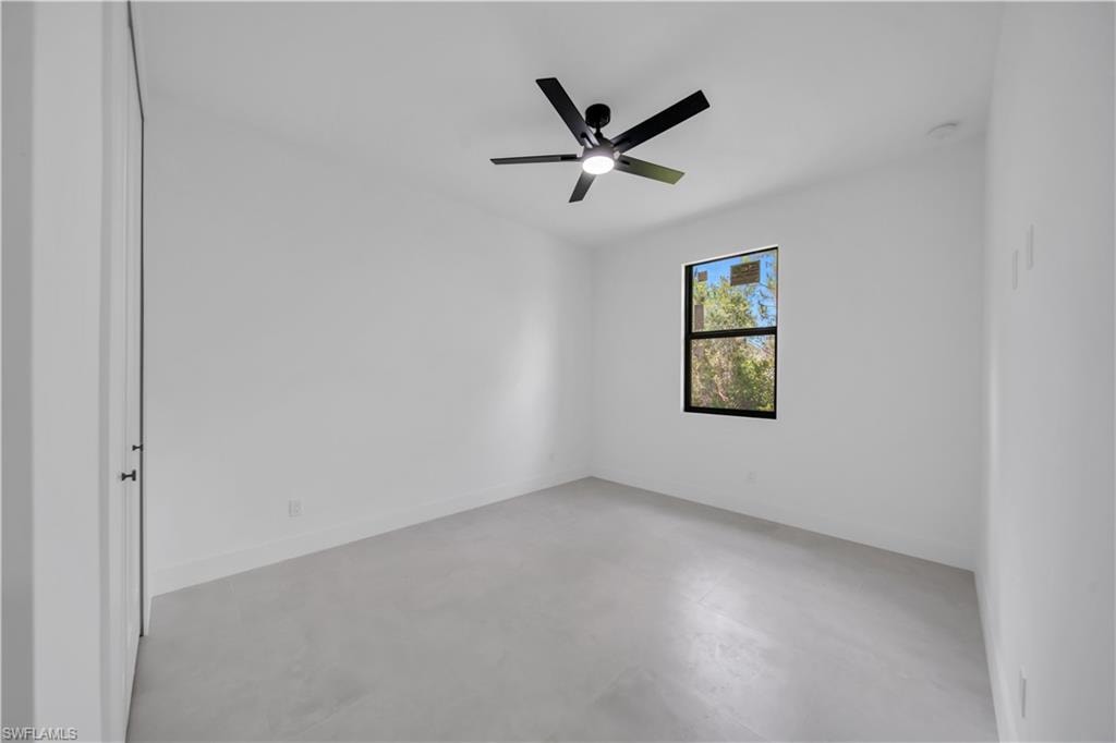 Contemporary room featuring a black ceiling fan with integrated lighting, a single window with black trim, and light-toned flooring