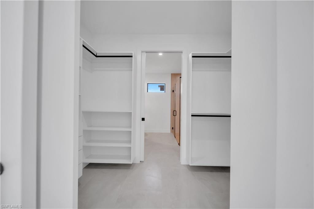 Walk-in closet with built-in shelving, hanging rods, and light-toned flooring