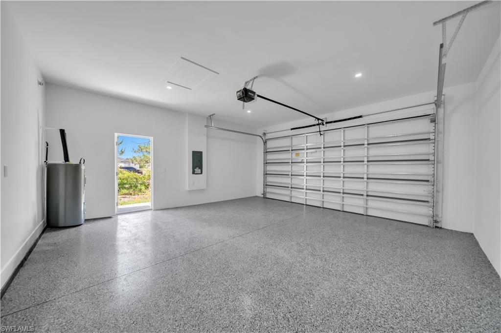 Spacious garage featuring a durable epoxy-coated floor, automatic overhead door, and recessed lighting