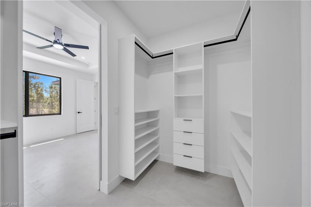 Walk-in closet with built-in white shelving, integrated drawers with black pulls, and hanging rods
