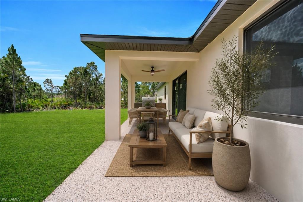 Expansive covered patio with a ceiling fan, light-colored stucco exterior, and gravel hardscaping