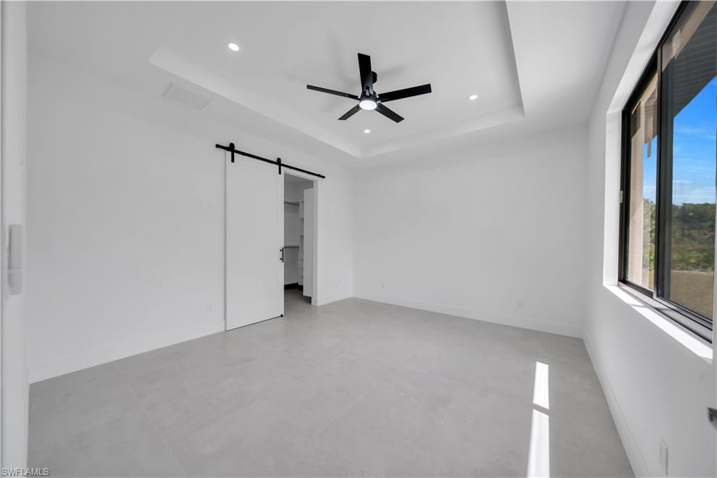 Spacious room featuring light gray tile flooring and a tray ceiling with recessed lighting