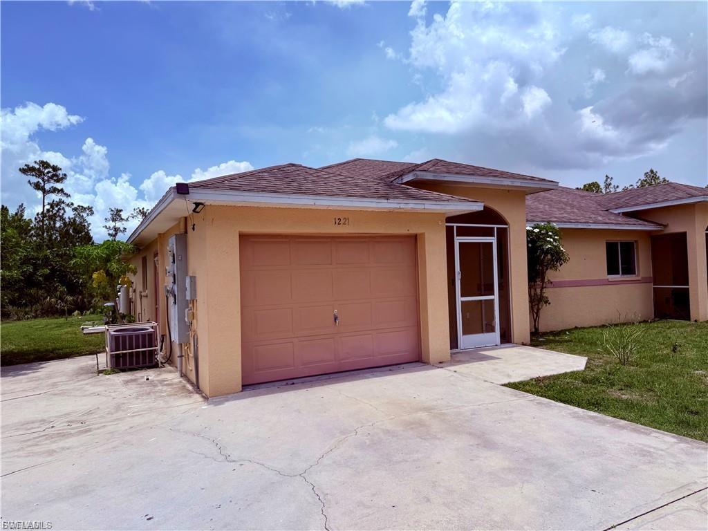 Ranch-style house with stucco siding, driveway, a shingled roof, and an attached garage