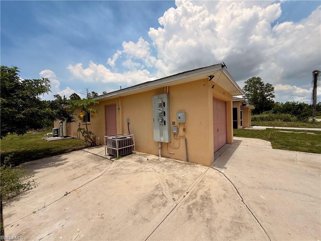 View of side of home with stucco siding, concrete driveway, an attached garage, a patio, and a lawn