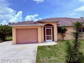 View of front of home with driveway, a front yard, an attached garage, and stucco siding