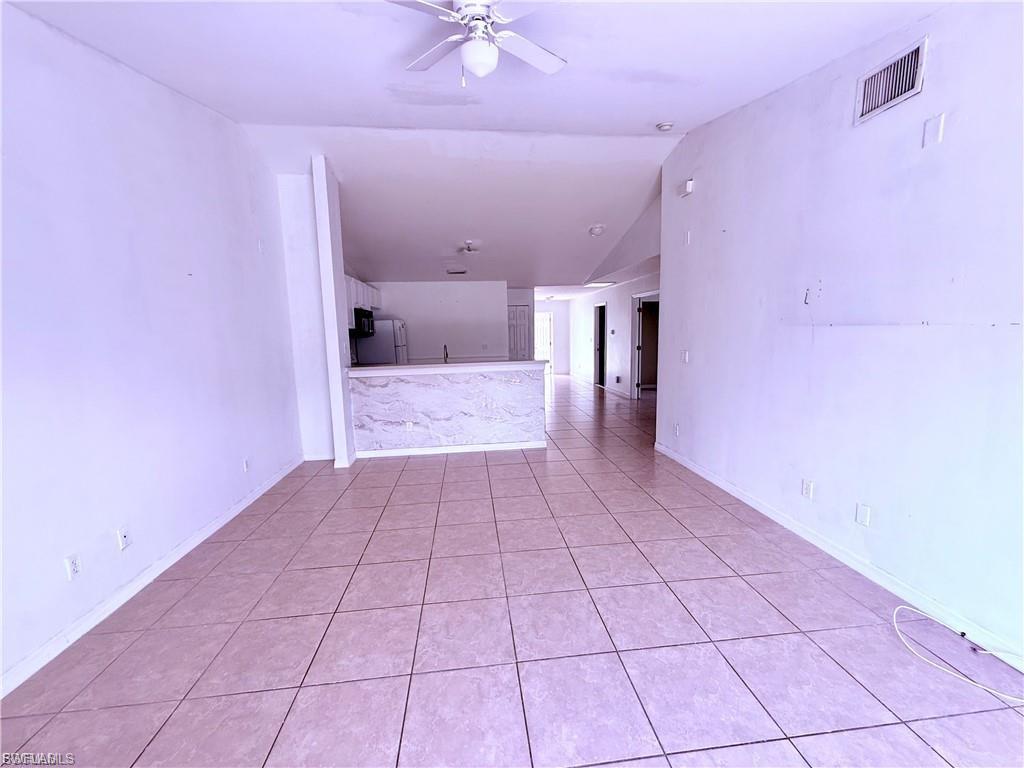 Spare room featuring lofted ceiling, light tile patterned flooring, and a ceiling fan