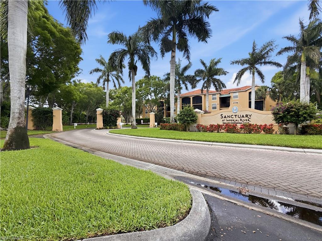 Paver brick entranceway with lush green landscaping and mature palm trees