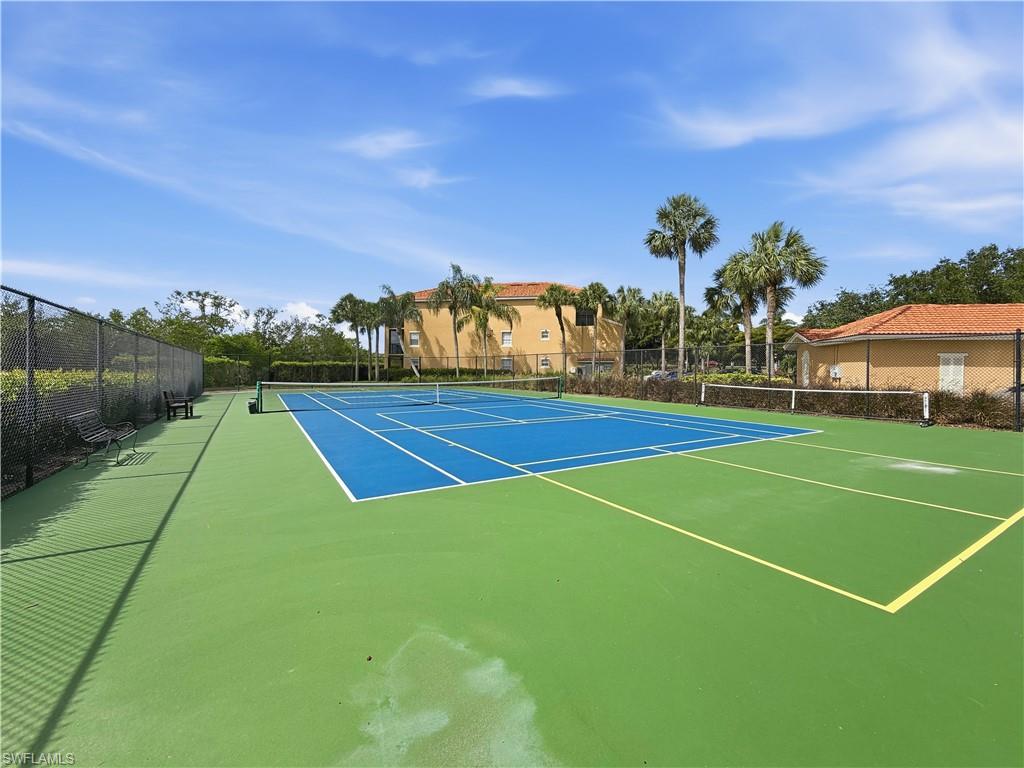 Full-sized tennis court with a blue playing surface and green surrounding area