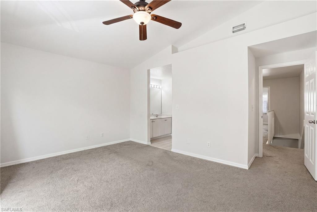 Carpeted room featuring a vaulted ceiling and a ceiling fan with integrated lighting