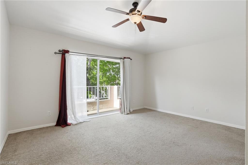 Carpeted room featuring a ceiling fan, sliding glass door, and a private balcony with white railings