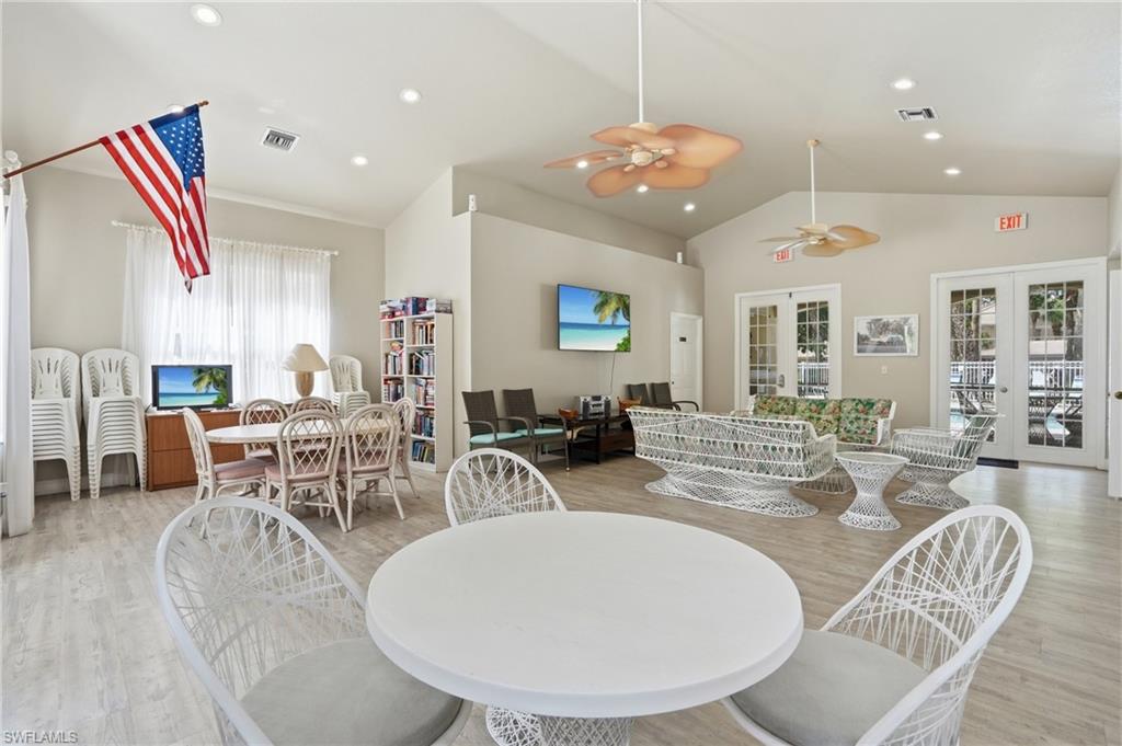 Spacious common area featuring vaulted ceilings, recessed lighting, wood-finish flooring, two sets of double French doors, and two ceiling fans