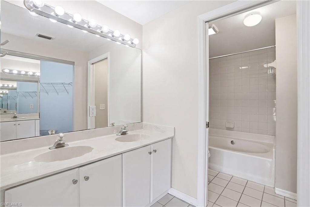 Dual vanity with integrated sinks, white cabinetry, and a large wall-mounted mirror