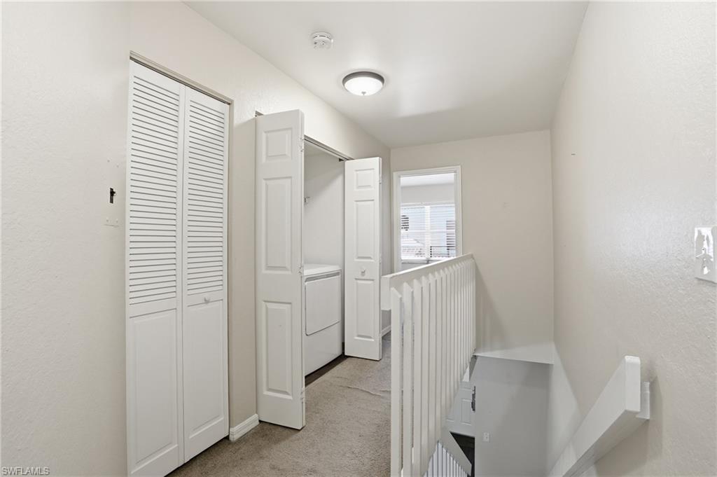 Laundry area featuring a stacked washer and dryer, white louvered bi-fold doors, and recessed ceiling lighting