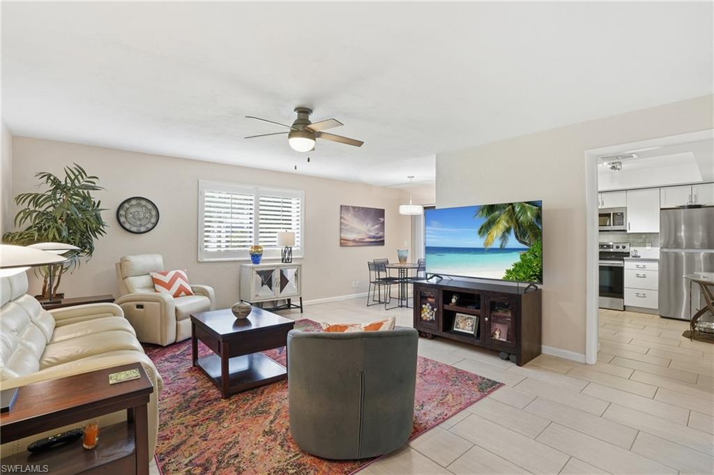 Living area featuring a ceiling fan, window with white louvered shutters, and tile flooring