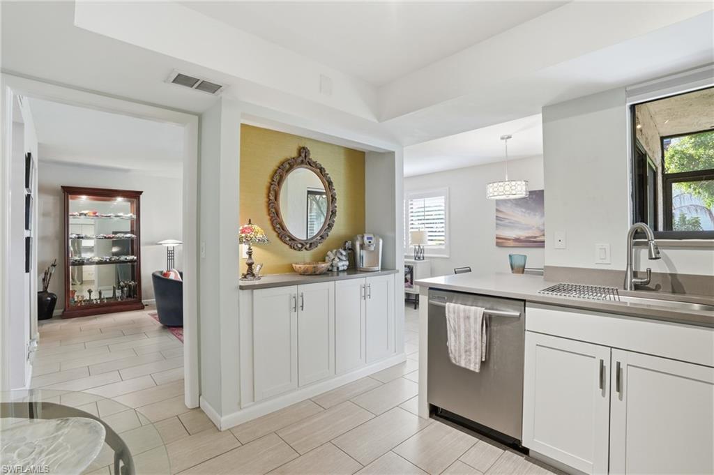 Modern kitchen featuring white cabinetry, light countertops, and a stainless steel sink with a gooseneck faucet
