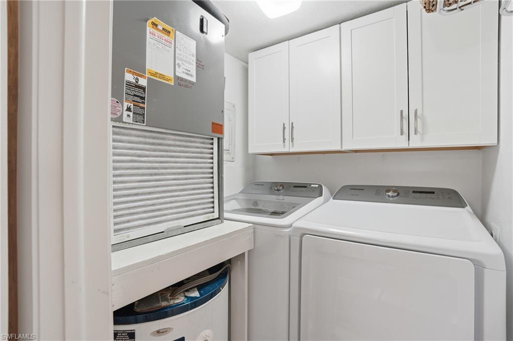Dedicated laundry area featuring white shaker-style cabinetry, overhead lighting, and white walls
