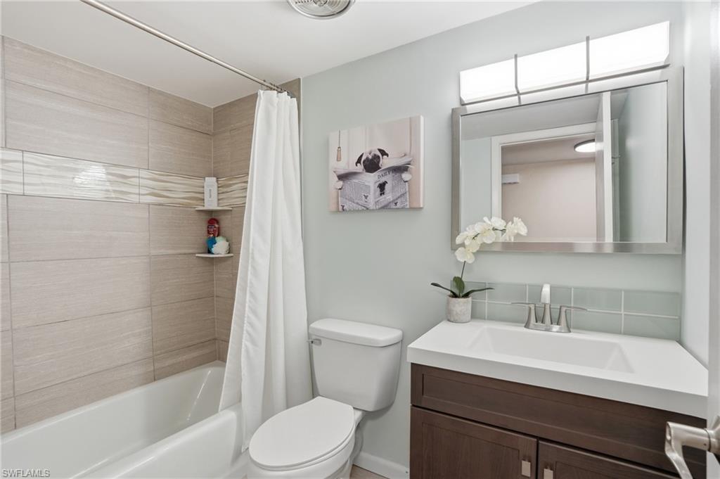 Bathroom featuring a tub/shower combination with light-toned horizontal tile, a floating vanity with an integrated sink, a rectangular mirror, and a contemporary light fixture